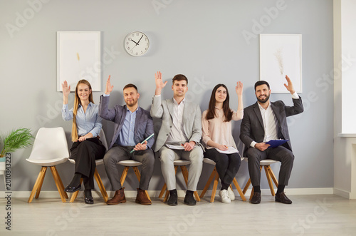 Foto Diverse office candidates raise hand answering questions sitting on chairs in ro