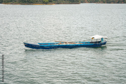 Blue cargo boat navigating reservoir at guatapé, colombia