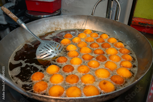 Deep frying fritters in large pan with hot oil