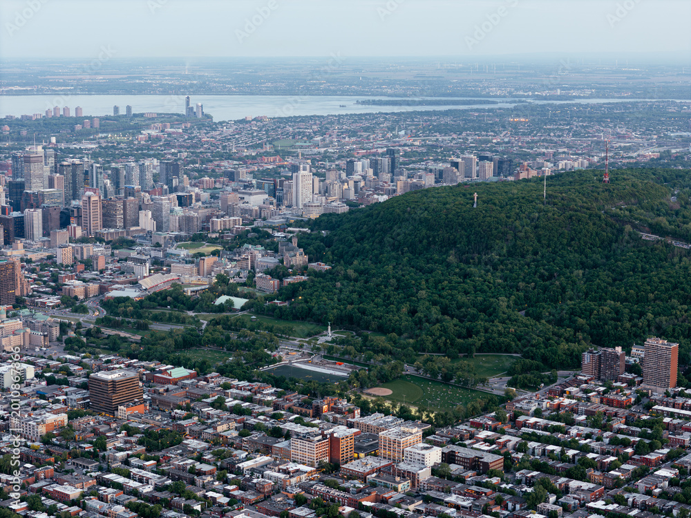 Obraz premium Aerial view of Montreal city skyline with residential grid, river and Mount Royal at sunset. g.
