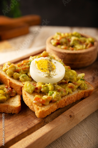 Schilderij op canvas Avocado toast, a healthy breakfast of toasted bread with mashed and seasoned avocados, boiled eggs, salsa and spices, an easy and healthy homemade recipe option for breakfast or a snack