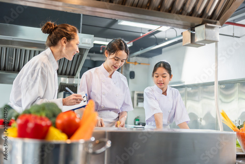 Foto Professional female chef teaching young students in industrial kitchen classroom