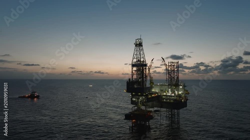 Aerial top view of offshore jack up rig and offshore platform during sunset for oil and gas exploration and production. 