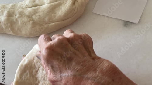 A close-up captures hands skillfully stretching and expanding the edges of a dough wrapper to prepare it for filling during the handmade baozi making process.