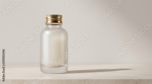 Frosted glass bottle with gold cap on a marble surface