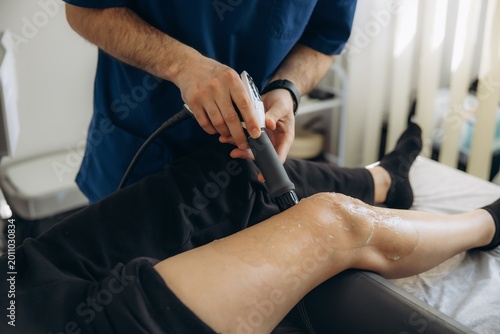 Physiotherapist performing shockwave therapy on patient's knee