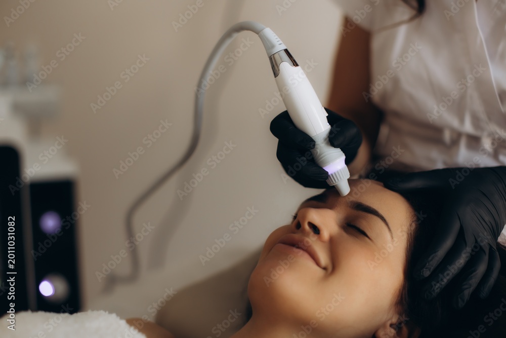 Fototapeta premium Woman receiving modern facial skincare treatment in beauty salon. Facial hydropeeling
