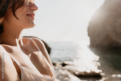 Schilderij op canvas Woman ocean sunlight smiling in white lace camisole on coastal shore during gold
