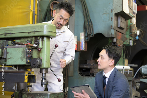 製造業の機械のメンテナンスや新しい機械の購入(設備投資)や融資などを説明する作業員と営業マン　中小企業の工場のdxの商談イメージ