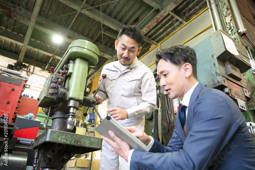 製造業の機械のメンテナンスや新しい機械の購入(設備投資)や融資などを説明する作業員と営業マン　中小企業の工場のdxの商談イメージ