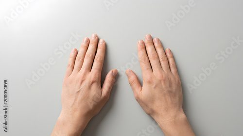Two hands with palms facing down on a gray surface