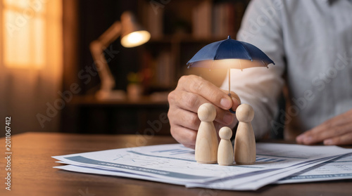 Wooden family figures sheltered by a small umbrella on financial documents, symbolizing insurance, financial protection, risk management, security and planning for family wellbeing and business stabil