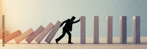 Businessman pushing dominoes in a row with one hand, symbolizing leadership and cause and effect