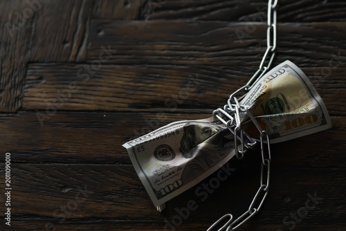 Фотография Chained Hundred-Dollar Bill on Dark Wooden Background: Symbol of Financial Const