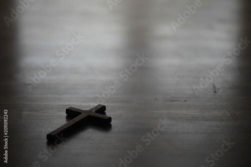 Fotografie Wooden Cross on Dark Wooden Surface with Soft Light in Background for Spiritual