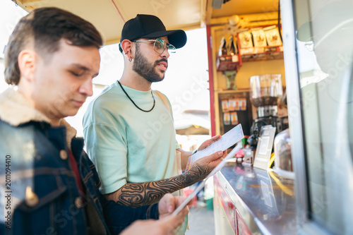 Two Latino men look at the menu at a street food stall