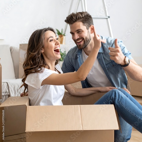 Happy couple celebrating moving day with cardboard boxes and furniture
