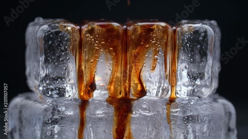 Caramel syrup dripping over iced coffee with ice cubes creating rich sweet texture macro close up beverage