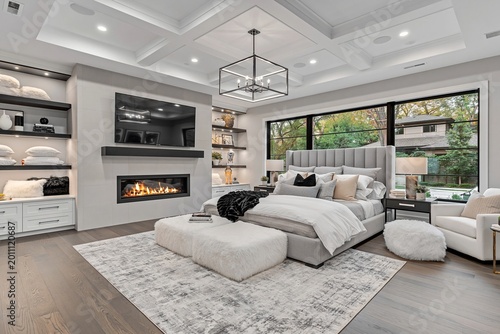 Bedroom features a modern interior design with a king size bed, a fireplace, custom built-in shelves, and high-end furniture pieces arranged to create a luxurious and peaceful living environment.