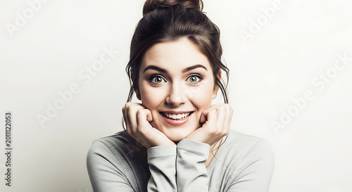 Portrait of charming woman with cute smile looking at camera with wide open eyes.