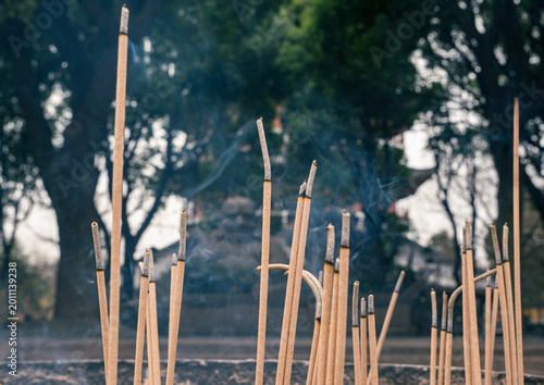 Valokuva Incense sticks burning in a park during the morning with trees and smoke rising