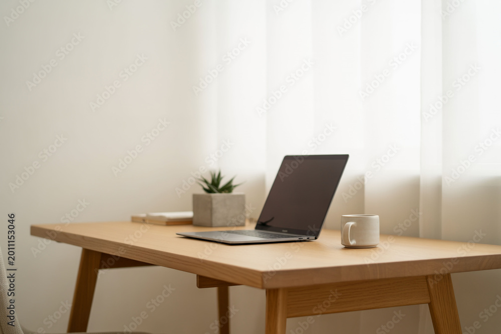 Fototapeta premium Modern home office, wooden desk with laptop, plant, and coffee cup, minimalist workspace