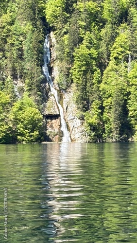 Waterfall Flowing into Calm Forest Lake in Scenic Mountain Landscape