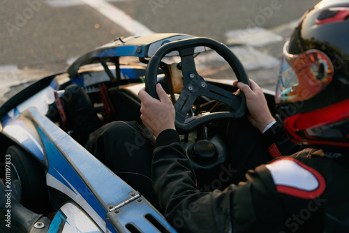A focused racer grips the steering wheel of a go-kart, ready to hit the track
