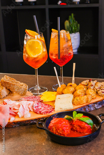 Foto Aperitivo servito in un bar con spritz, tagliere di salmi e formaggi, polpette a