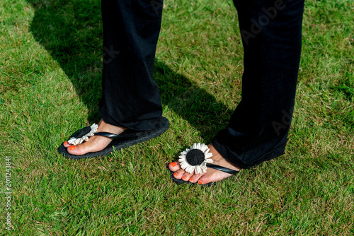 Fotografie Footwear with flower designs stands out on grass at a sunny outdoor event in the
