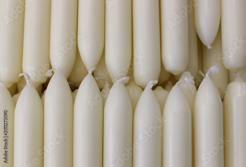 Fotografie Identical paraffin candles with white protruding wicks are laid out in order