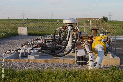 Billede på lærred Industrial oil lye mixing station with pipes valves hoses and pressure gauges at fossil fuel production site under blue sky