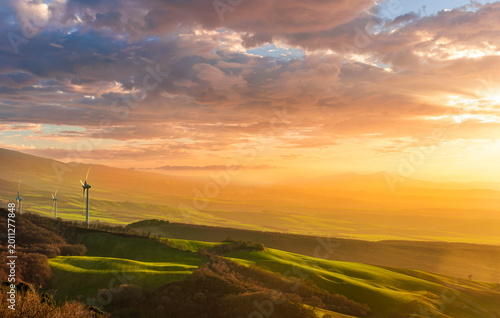 wind turbines of wind power plant producing electricity on green sunset hills on background of landscape. Concept of green energy and environment