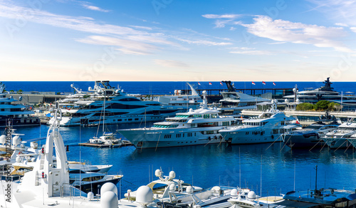 Luxury boat motor yacht in marina on Monte Carlo Bay. Sailboat moored to pier in yacht marina. Sailing and yachting tourism. Luxury Monaco lifestyle. Vacations on summer. Yacht at sea port.