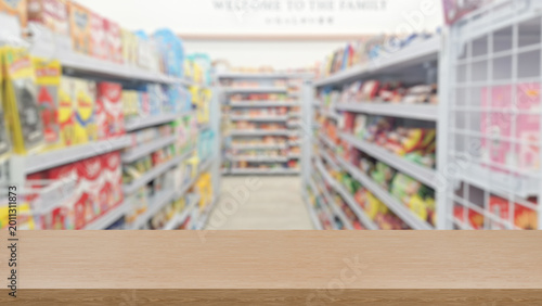 Tableau sur toile Empty wooden counter in Blurry shot of a grocery store aisle filled with various products