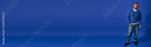фотографія Stylish man posing confidently in casual attire against a vibrant blue backdrop