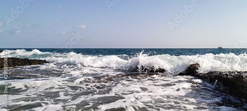 Crashing white sea waves over dark rocks illustrating dynamic ocean surf environments. Suitable for marine biology articles, coastal weather reports, and summer tourist websites.