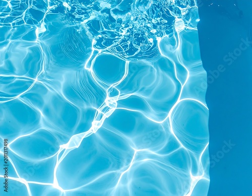 Pool water shimmers with sunlight creating abstract patterns near the edge with contrasting blue