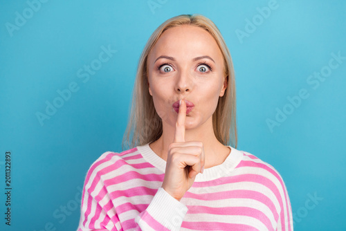 Foto Blonde woman with finger to lips signaling silence and secret on blue background