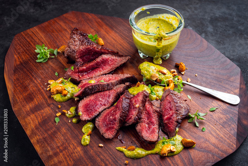 Broiled tagliata di manzo under-blade steak chuck, denver cut beef steak meat with basil peppermint sauce dip served as close-up on wooden board
