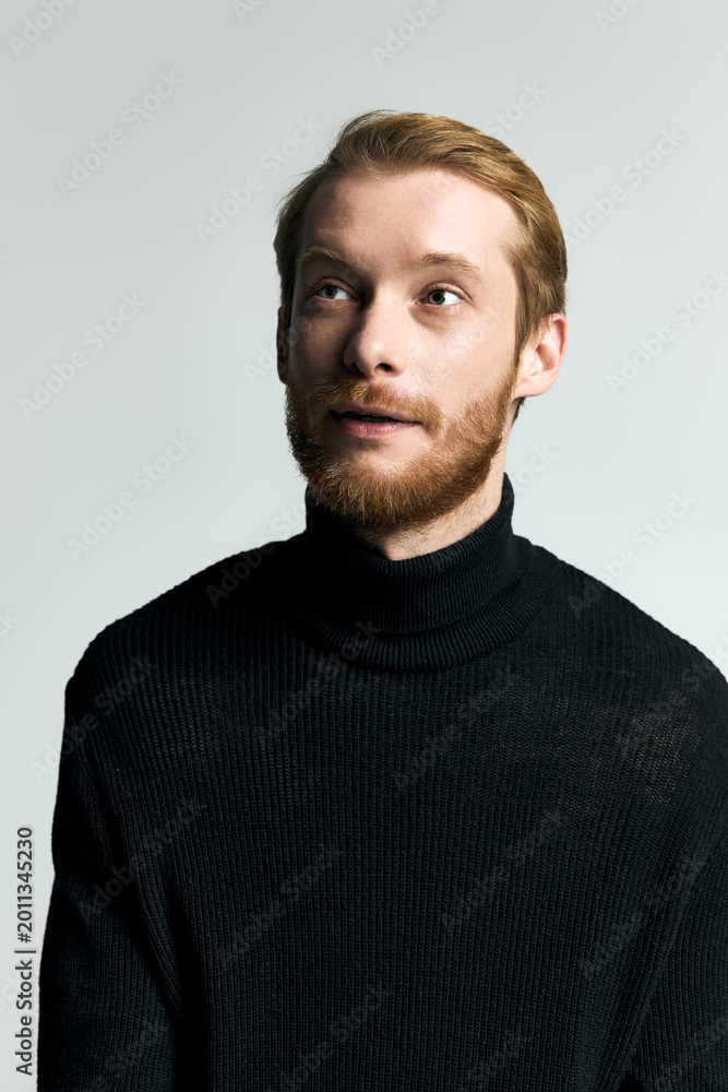 Fototapeta premium Handsome young man showcases stylish fashion in a modern setting with a thoughtful expression