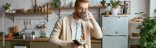 Cuadro en lienzo Stylish young man enjoying coffee while jotting down thoughts in a cozy kitchen setting