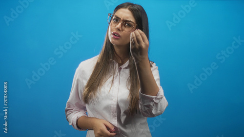 Bild auf Leinwand Young hispanic woman wearing glasses making a beckoning hand gesture while looking skeptical in a studio; frustration inquiry