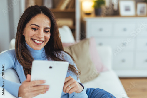 Smiling Woman Relaxing on Couch Browsing on Tablet in Cozy Living Room at Home Free Download Smiling Woman Relaxing on Couch Browsing on Tablet in Cozy Living Room at Home - GFXLoad