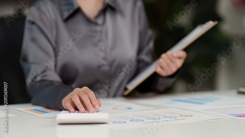 Schilderij op canvas Asian woman in 20s calculating finance data with calculator