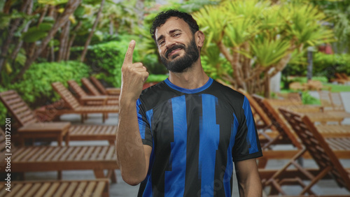Billede på lærred Soccer player man in blue black uniform showing three fingers with bare hand raised in forest resort poolside setting; confidence swagger