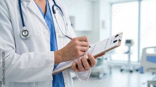 Health professional writing on a patient history form with a pen in a clinic room.