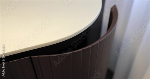 Ribbed wood vanity door in luxury bathroom interior, close video shows hand guiding curved cabinet front as it softly closes beneath pale stone countertop highlighting premium joinery smooth motion