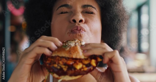 Happy, woman and burger in diner with delicious flavor, tasty cuisine and eating fast food for lunch. Hungry, person or customer in restaurant with beef sandwich, take away or meal for unhealthy diet