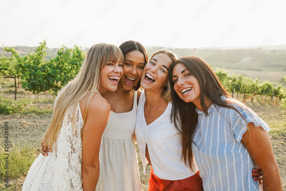 Naklejka premium Group of female friends having fun at summer event in countryside with vineyards in background - Summer vacation, party and travel concept - Focus on girls faces